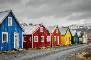 Rangée de maisons colorées traditionnelles au Groenland avec façades peintes en rouge, bleu et jaune vif sous un ciel arctique nuageux